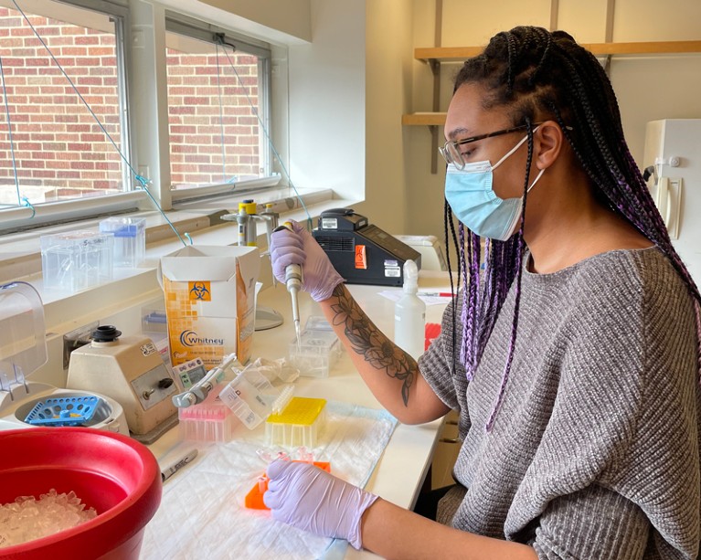 Ashley Paynter working in the lab while wearing gloves and a face mask