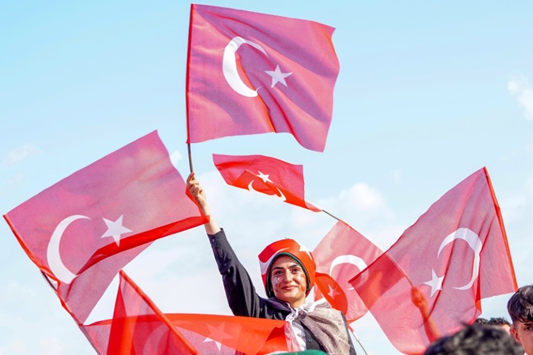 People wave Turkish flags, red with a white crescent moon and star.