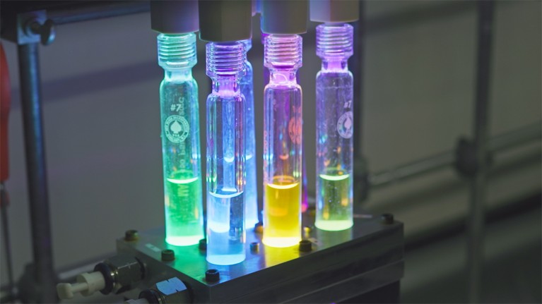 Close-up of five glass tubes containing blue, yellow or green liquid during the photocatalyst-development process.