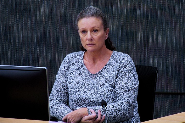 Una donna seduta in tribunale con un microfono davanti a sé.