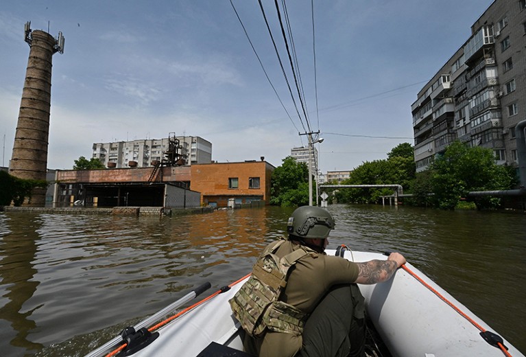 A serviceman of the National Guard of Ukraine sails on boat during a food delivery to the residents of a flooded area in Kherson