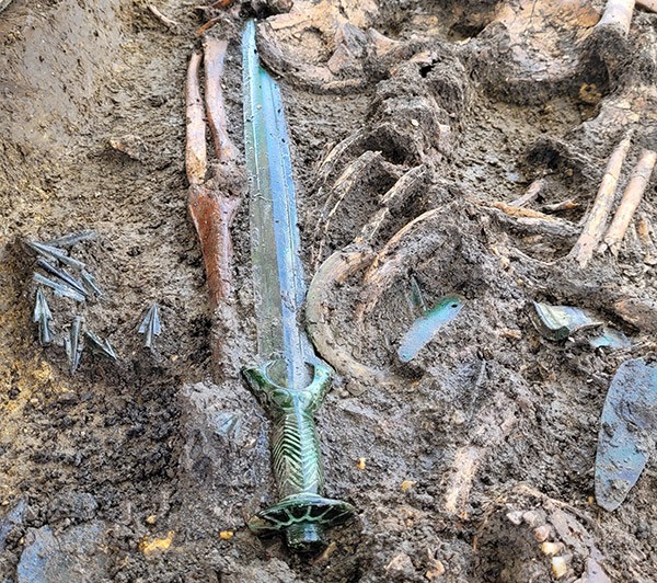 The Nördlingen Bronze age sword shown in situ partly buried in the soil alongside bone remains