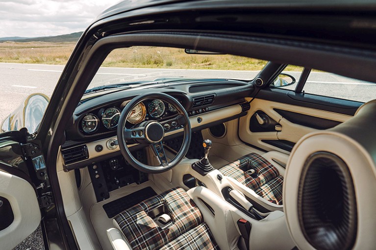 Interior car design, showing the dashboard and the fabric seats with a black metal exterior.