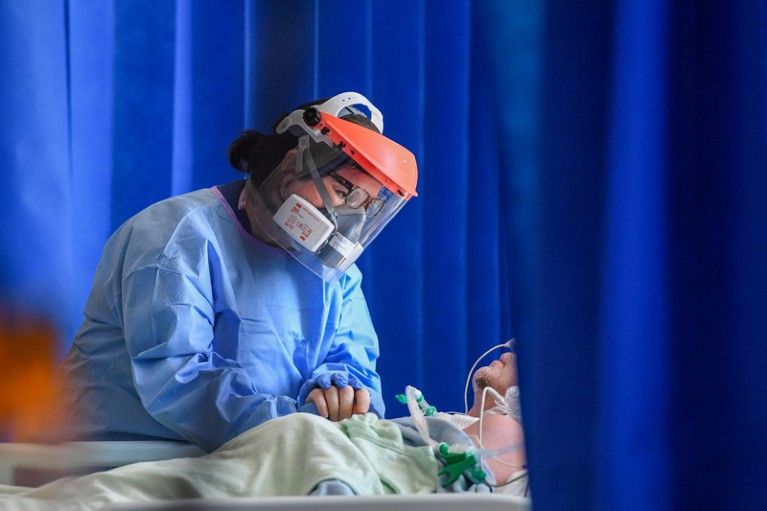 Close-up of a medical worker wearing PPE caring for a patient in the Intensive Care unit