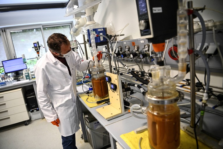 A lab technician wearing a face mask fills vials with a liquid solution to separate rare earths from mining waste