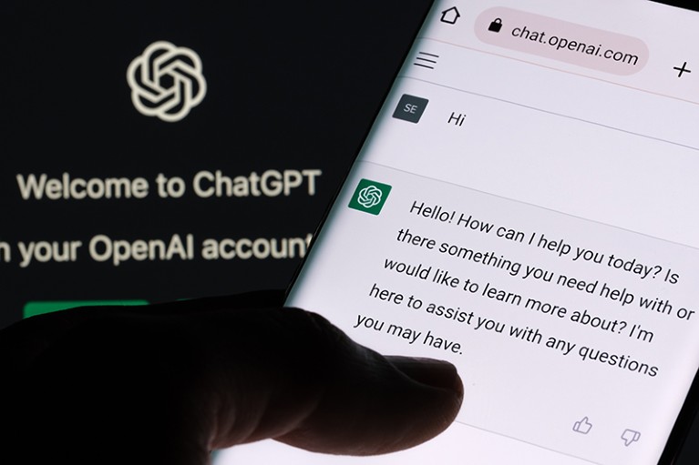 The ChatGPT chatbot on a smartphone display with the login screen on a laptop monitor in the background.