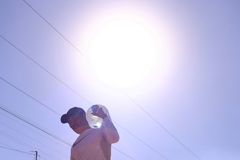A man carries a container filled with water during high temperatures in the Anapra neighbourhood in Ciudad Juarez, Mexico.