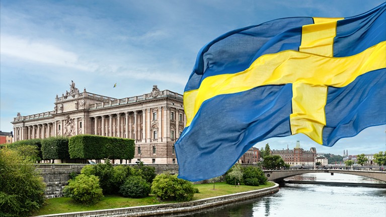 The Swedish parliament (Riksdag) with the national flag of Sweden in the foreground.