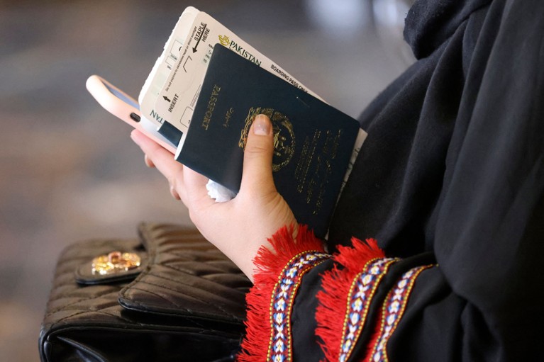 Close-up of a woman holding her passport, boarding pass and phone