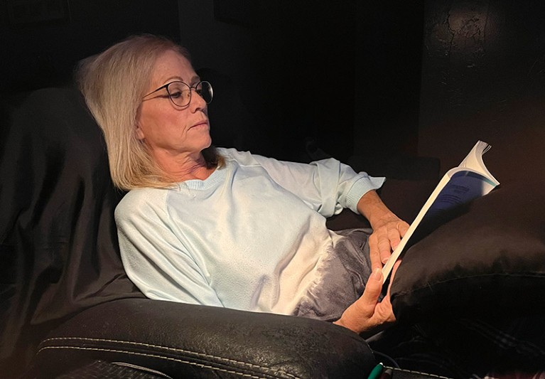 Lisa McLaughlin relaxing at home reading a book in a darkened room