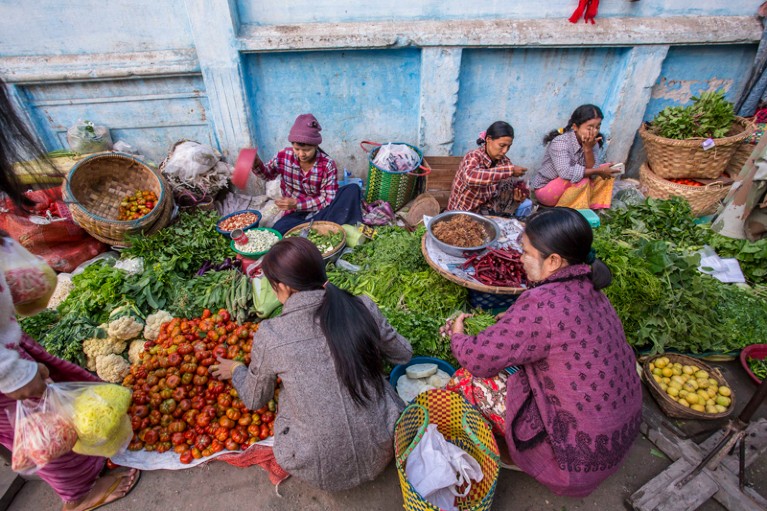 Mujeres vendiendo y comprando productos en el mercado de verduras de Mandalay