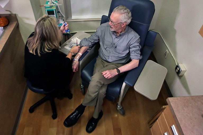 A patient talks to a clinician in a medical room while receiving an infusion of the drug Aducanumab in 2019.