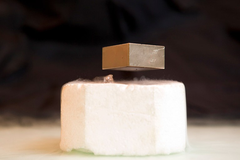 A metal cube is floating above a superconducting magnet cooled by liquid nitrogen