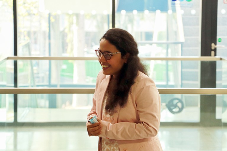 Payel Das smiling post-PhD defense in a glass-walled lecture room.