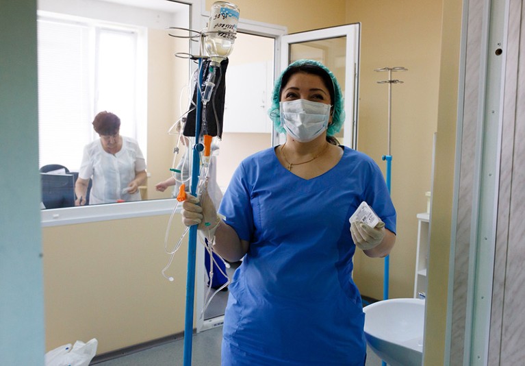A nurse stands in a chemotherapy unit holding cancer treatment