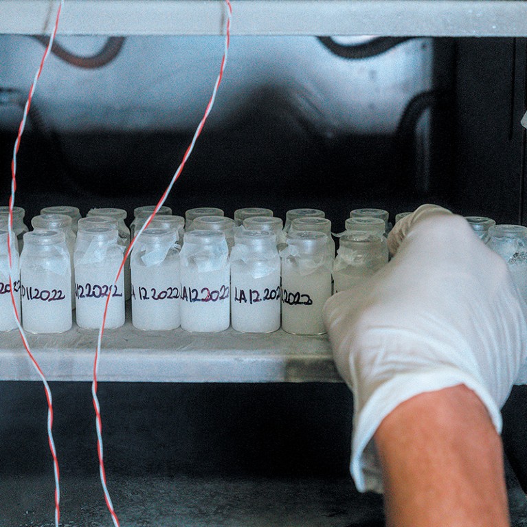A gloved hand reaches into a fridge filled with vials of antivenom samples
