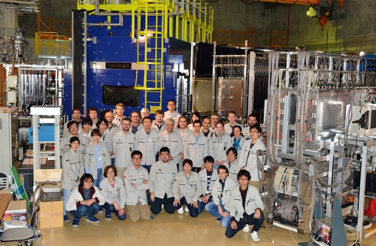 The a group photo of the team and the Oxygen-28 experiment setup at the RIKEN Radioactive Isotope Beam Factory.