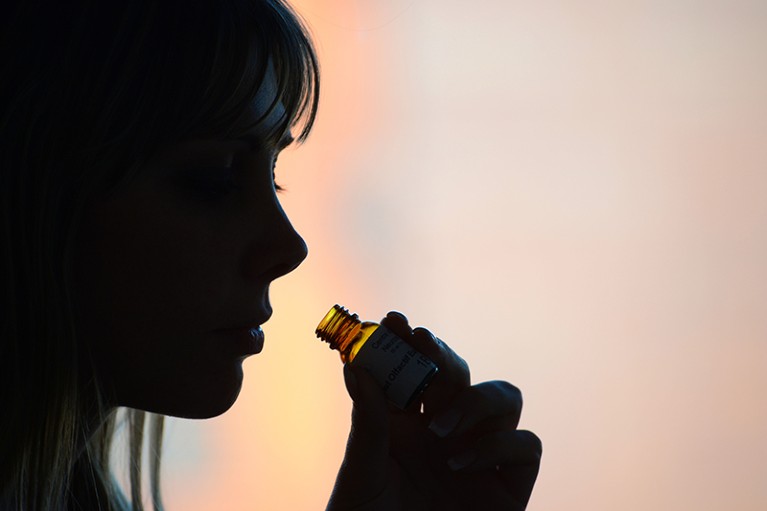 A young woman smells a small bottle of perfume during an olfactory test at the French National Center for Scientific Research.