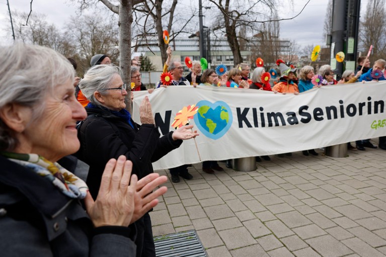 A group of Swiss retirees applaud and hold a banner that reads 'KlimaSeniorinnen'