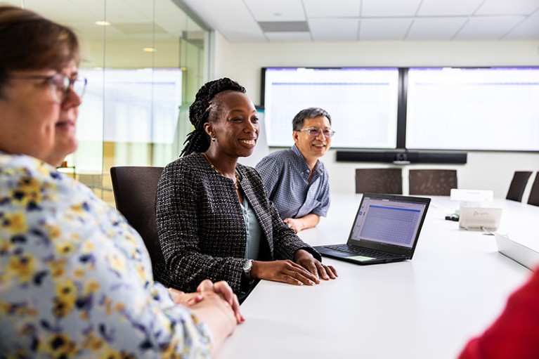 Elenoe Crew Smith (center) at a conference table in Vertex Pharmaceuticals headquarters, meeting with four colleagues.