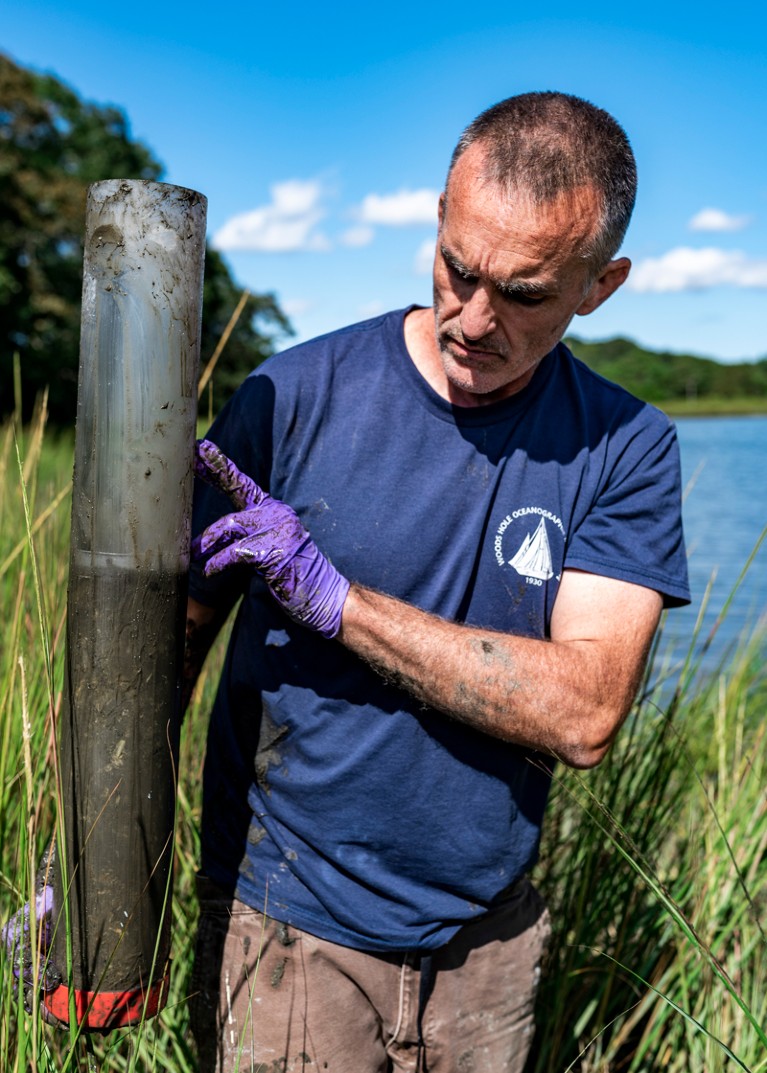 Chris Reddy holds a sediment core sample with purple gloved hands