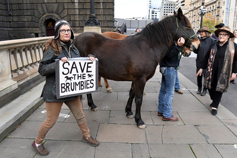 A woman holds a placard during a protest over the proposed culling of the horses, in Melbourne.