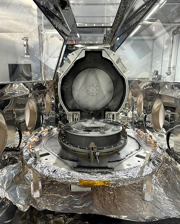 A view inside a glass and stainless steel glovebox containing the OSIRIS-REx asteroid sample return canister.