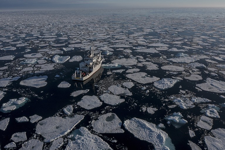 A ship is seen in the Arctic Ocean, surrounded by ice