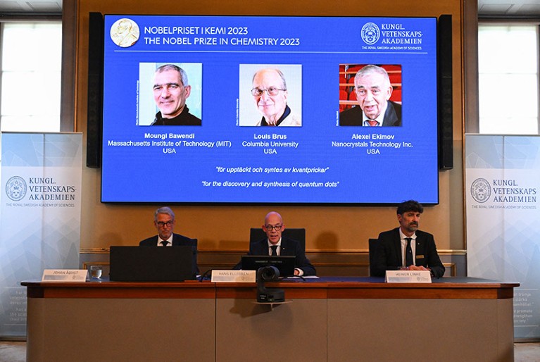 A screen shows Moungi Bawendi, Louis Brus and Alexei Ekimov during announcement of the 2023 Nobel Prize in chemistry.