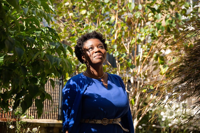 Person standing at centre of photo, looking upwards, trees in the background