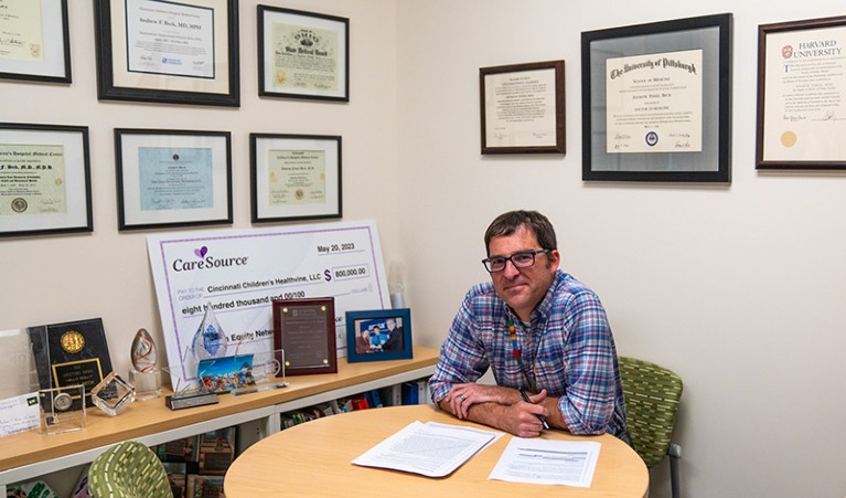 Person sitting at a table, framed pictures on the wall behind