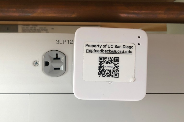 Close up of a white activity monitor plugged into a wall socket