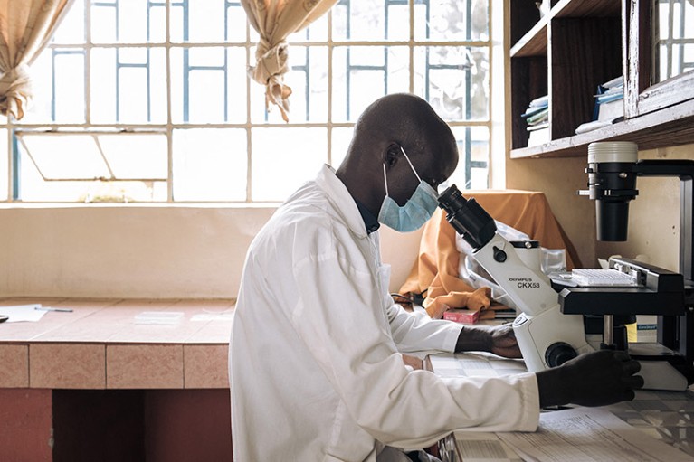 A laboratory technician in the Democratic Republic of the Congo uses a microscope.