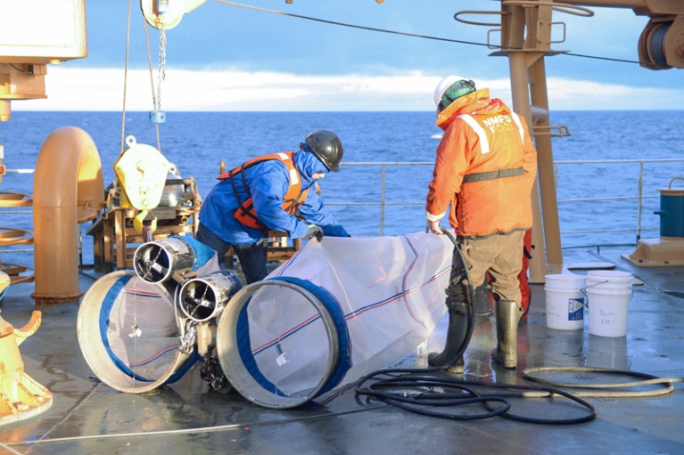 Two scientists rinse off bongo plankton nets on a boat