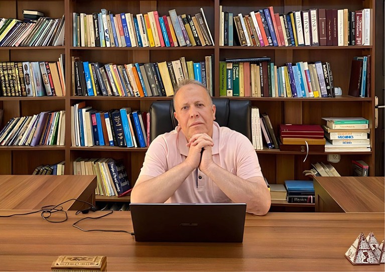 Imad Barghouthi at a desk in front of bookshelves.