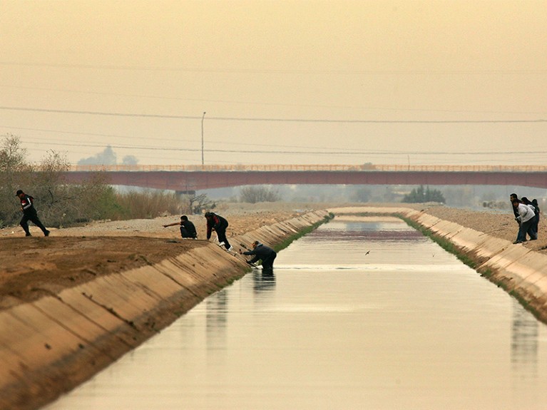 People cross a canal after walking over the dry Colorado River to cross illegally into the U.S. from Mexico.