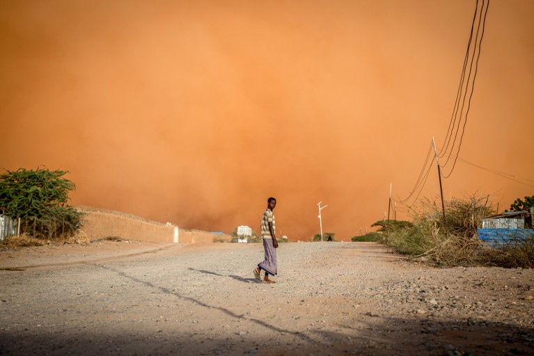 A man walks in front of a looming sandstorm in Somalia