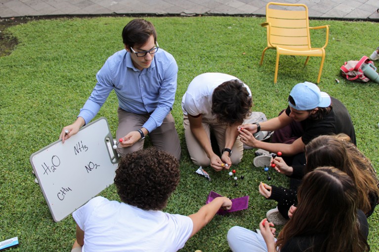 Joaquín Ramírez Ramírez teaches students with a whiteboard while sitting on the grass
