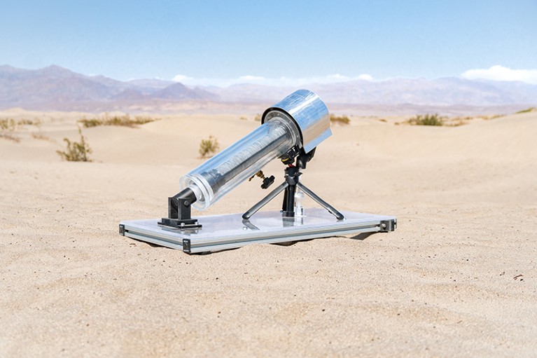 Instrument that resembles a small telescope is propped up on a flat panel in a sandy desert.