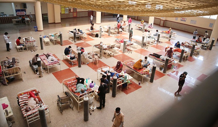 Aerial view of rows of hospital beds, some occupied by people