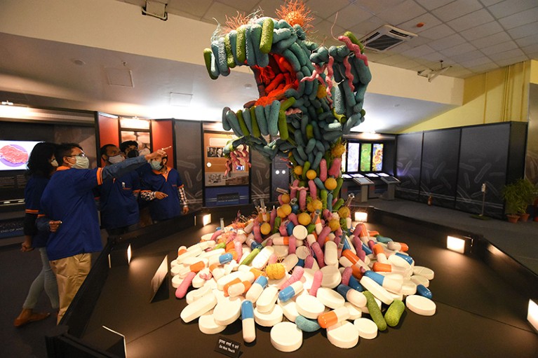 A group of people look and point at a sculpture at an exhibition about Superbugs