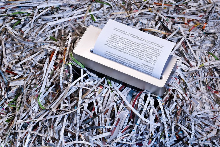 A shredder atop a huge pile of shredded paper documents.