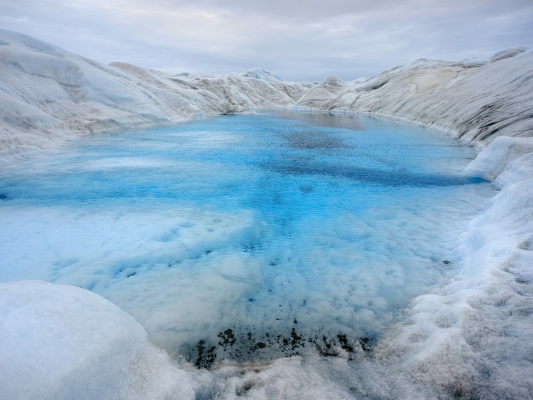 A lake forms from melting ice on the surface of Greenland's ice sheet.