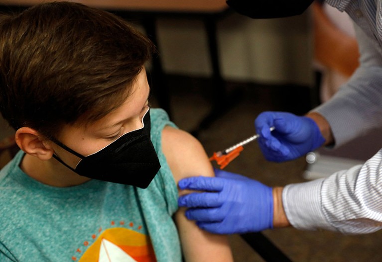 一名儿童从密歇根州布卢姆菲尔德山的一名药剂师那里接种辉瑞-BioNTech Covid-19 疫苗。