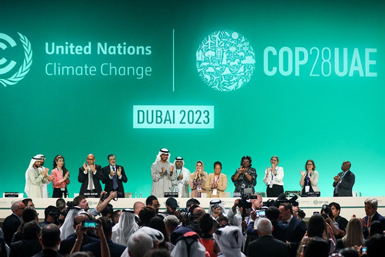 Delegates applaud after a speech by Sultan Ahmed Al Jaber (C) during a plenary session on day thirteen of the UNFCCC COP28 Climate Conference.