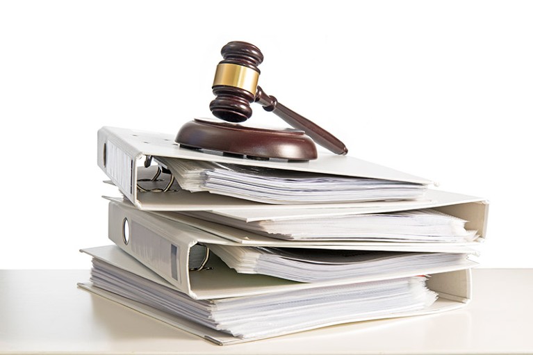 A stack of folders and a judge's gavel on a desk.