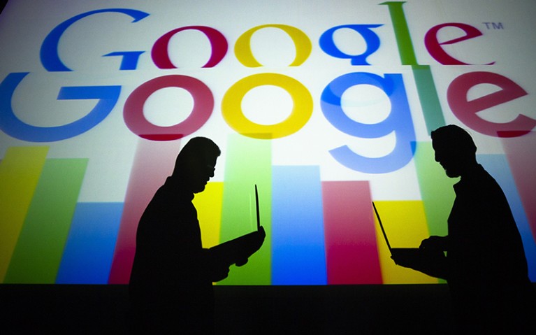 Silhouettes of people holding laptops are seen in front of the logo of 'Google' technology company, Turkey.