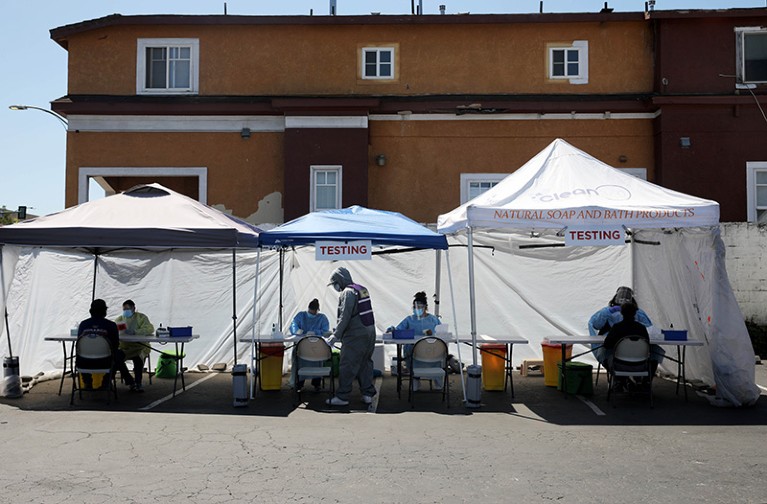 Staff members operate a coronavirus testing site in a white tent at Roots Community Health Center in Oakland, California, U.S. in 2020.