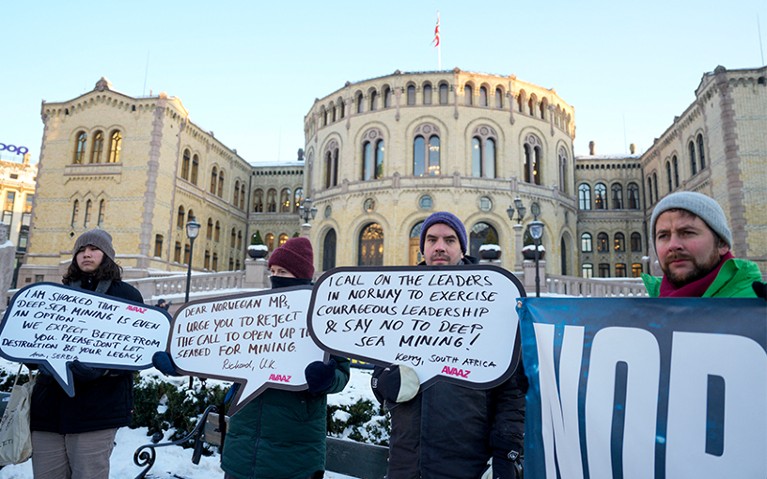 Protesters hold placards during a demonstration against seabed mining outside the Norwegian Parliament building, Oslo.