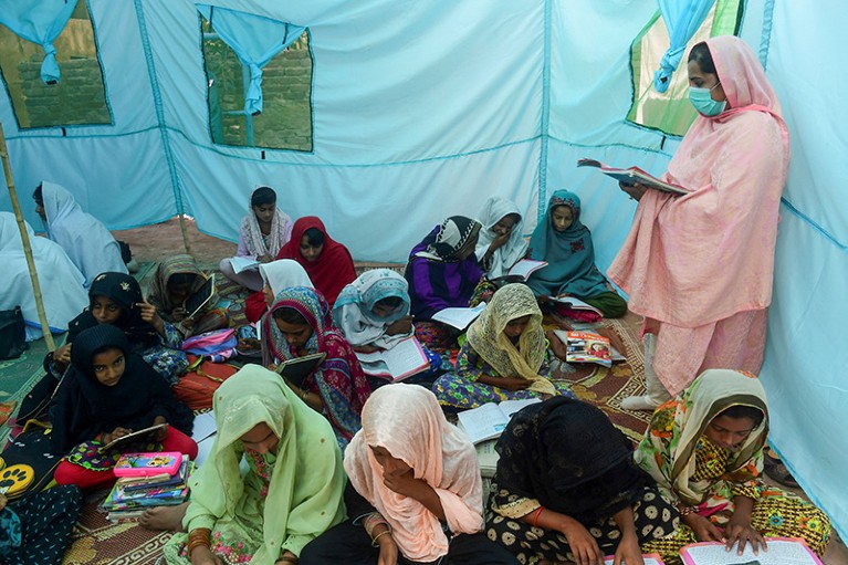 A teacher gives lessons to children in a makeshift tent school in the flood-affected Dadu district of Sindh province, Pakistan in 2022.